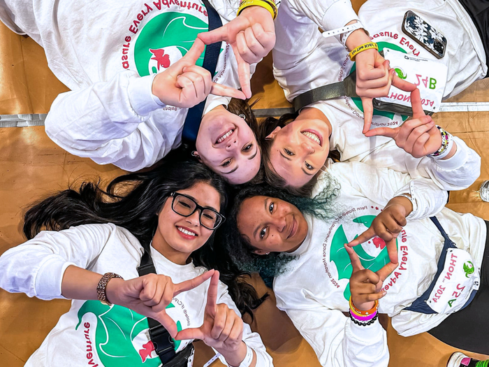 four young women lay on the ground in the shape of a diamond smiling 