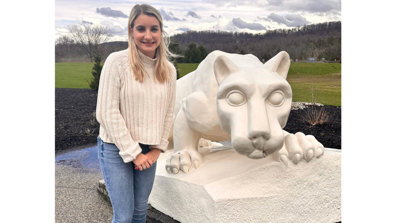 a female student standing in front of the lion shrine 