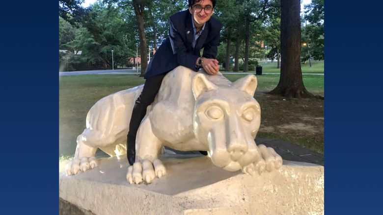 a male student smiling next to the lion shrine 