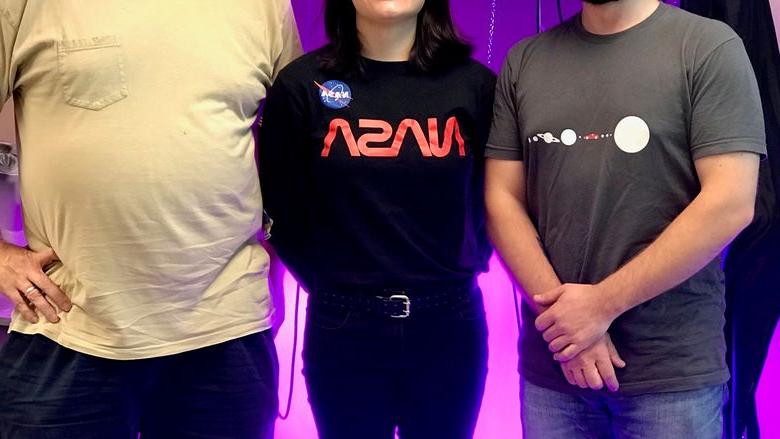 three people in front of bright purple lights