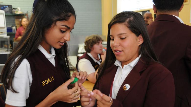 Two students examine a mini house from a 3-D printer